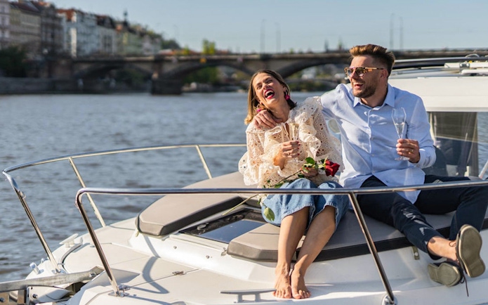 Couple enjoying Prague Beer Boat Tour with drinks on Vltava River.