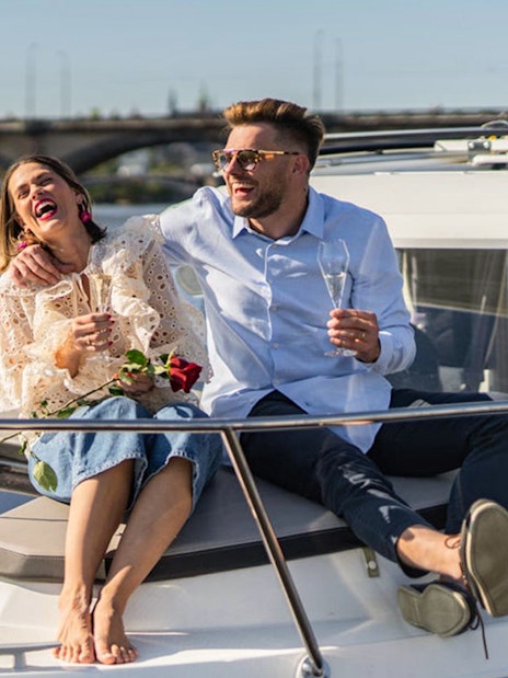 Couple enjoying Prague Beer Boat Tour with drinks on Vltava River.