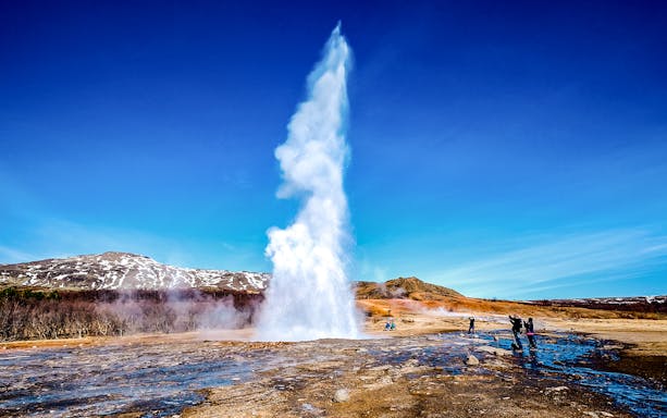 Geyser erupting in Icelandic landscape on Golden Circle tour from Reykjavik.