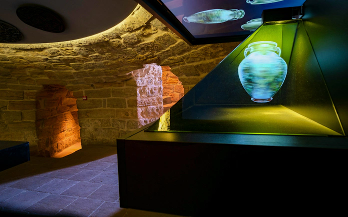 Interior of Maiden Tower Museum, Baku, featuring illuminated ancient pottery display.