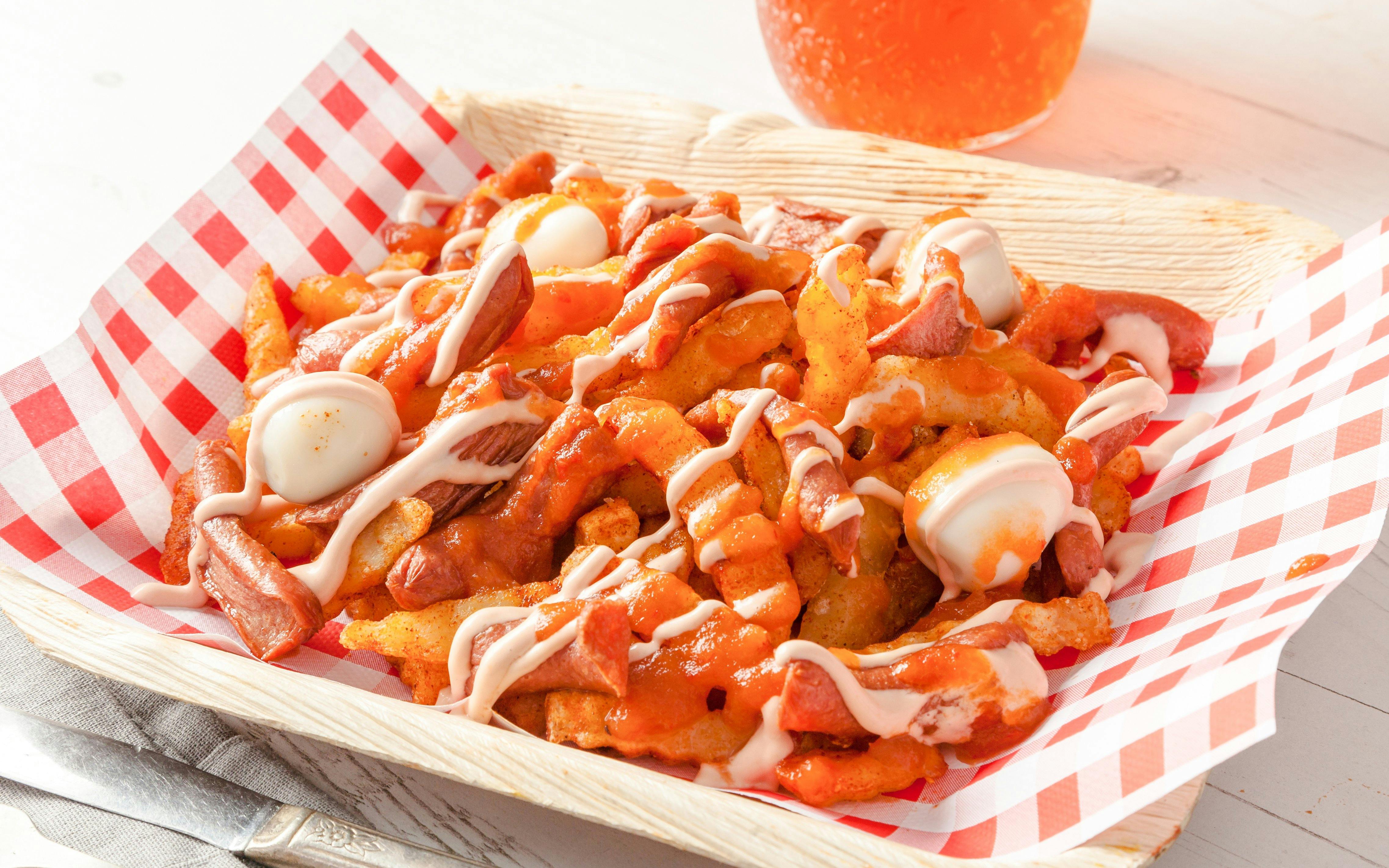 Colombian salchipapas with sausage, fries, quail eggs, and sauce in a basket.