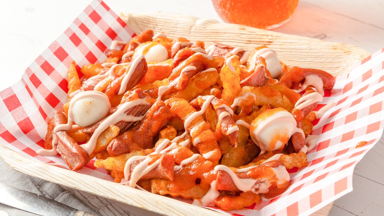 Colombian salchipapas with sausage, fries, quail eggs, and sauce in a basket.