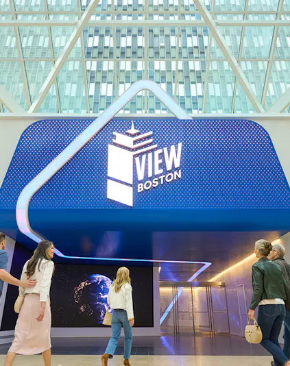Visitors entering View Boston with illuminated signage and glass building backdrop.