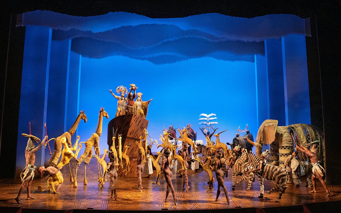 Stage performance of The Lion King in Brisbane with actors in animal costumes.