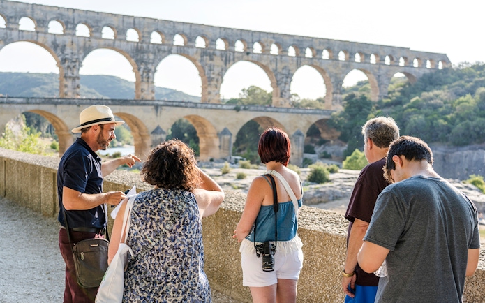 Tour group exploring Pont du Gard aqueduct in France.