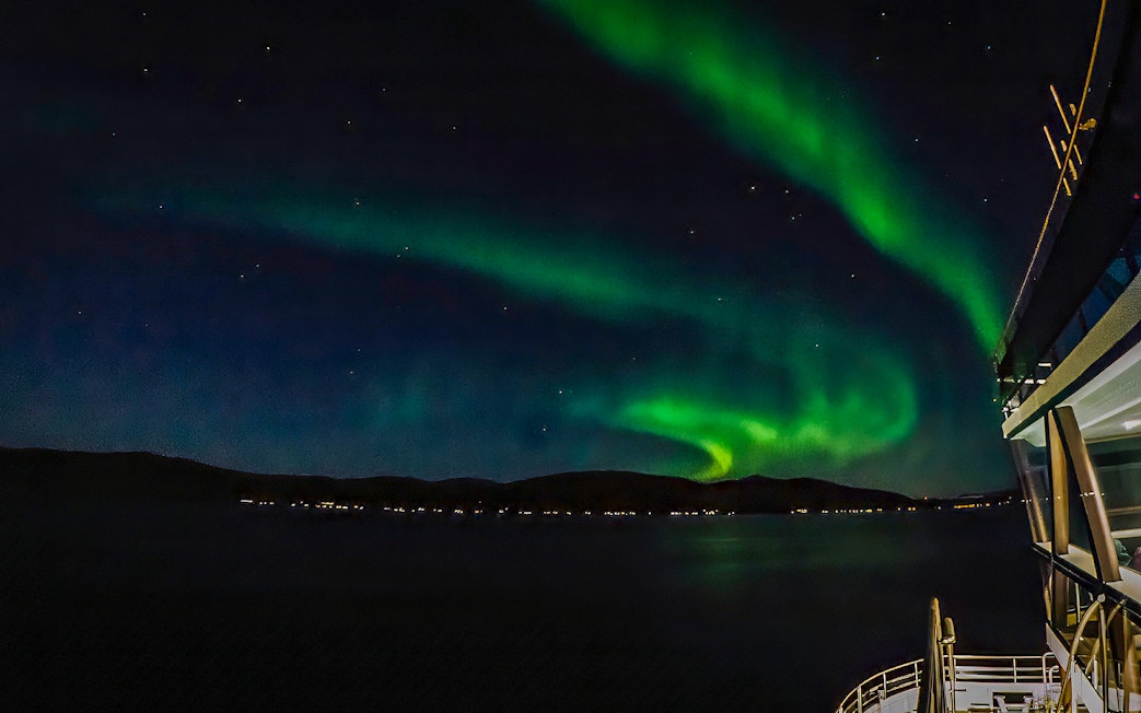 Northern lights over a cruise ship deck at night.