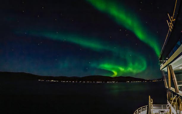 Northern lights over a cruise ship deck at night.