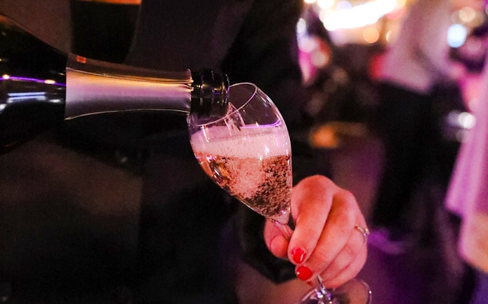 Waiter pouring champagne on Paris bus tour.