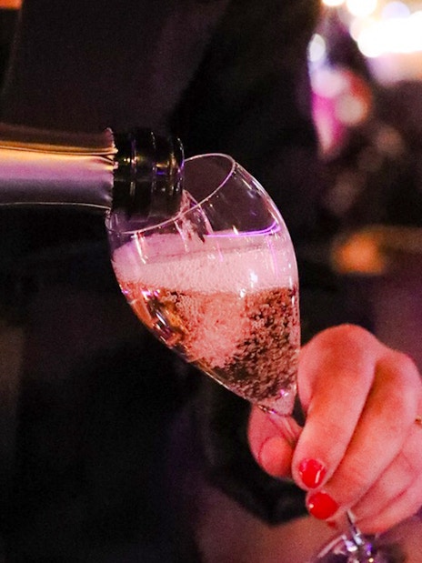 Waiter pouring champagne on Paris bus tour.