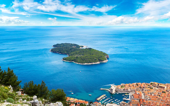 Lokrum Island in Dubrovnik, Croatia, surrounded by the Adriatic Sea with the city in the foreground.