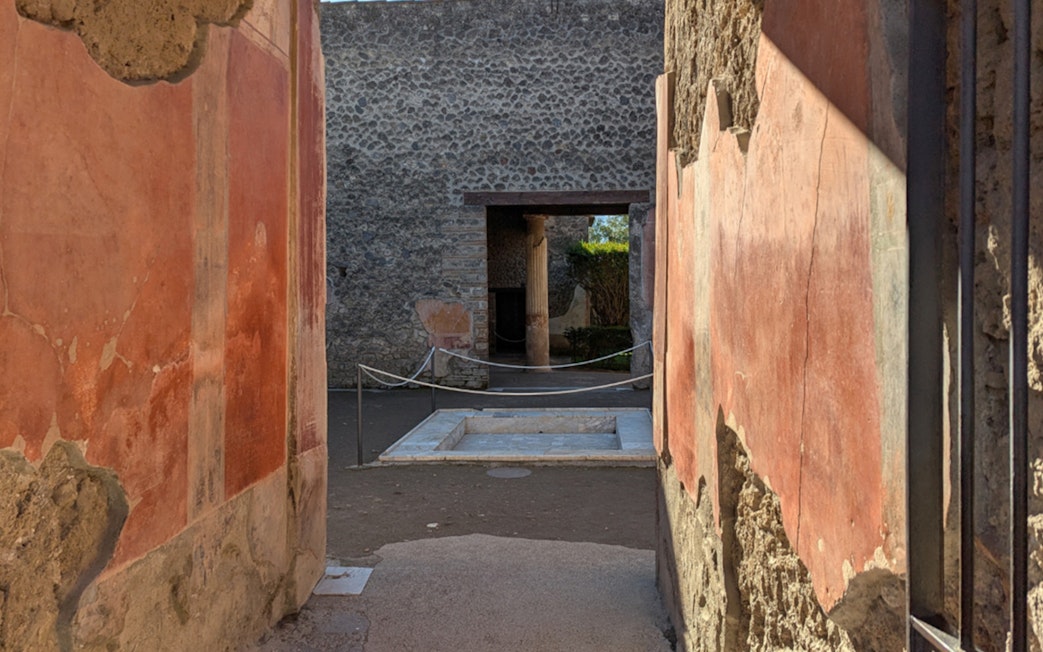 Ancient frescoed walls and courtyard in the ruins of Pompeii, Italy.