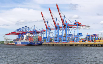 Container ship docked at Port of Hamburg with cranes, part of a unique harbor tour.