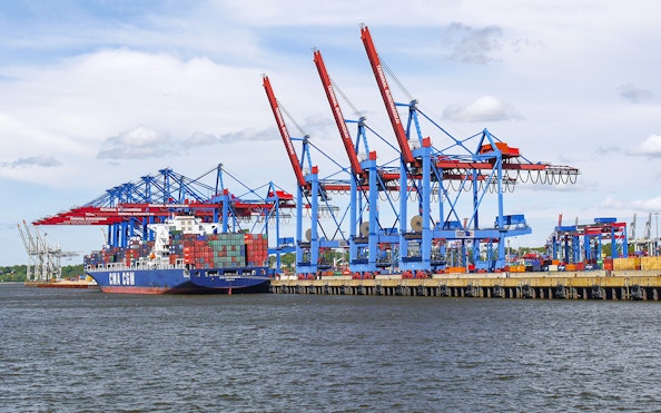Container ship docked at Port of Hamburg with cranes, part of a unique harbor tour.