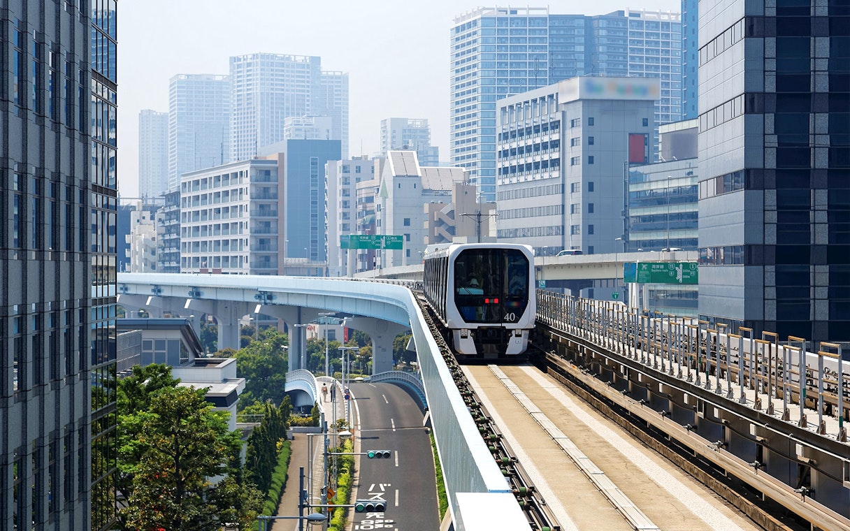Tokyo subway train on elevated tracks with city skyline in the background.