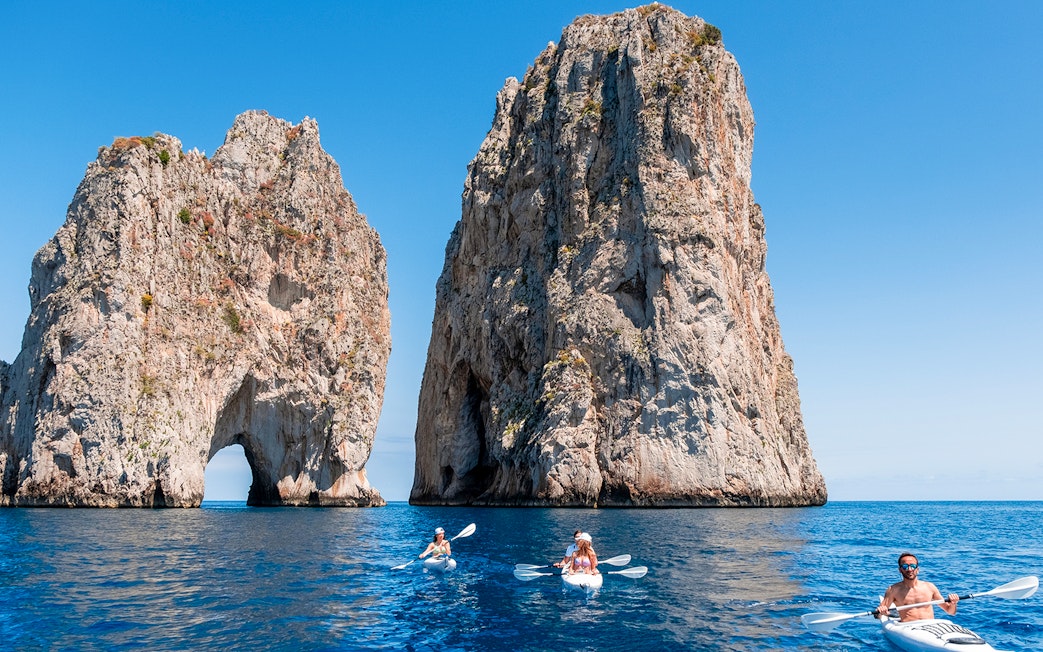 Kayakers near Faraglioni rock formations in Capri, Italy.
