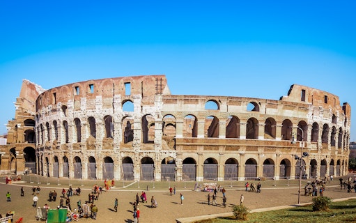 Colosseum in Rome with tourists exploring the exterior on a guided tour.