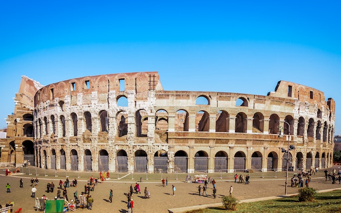 Colosseum in Rome with tourists exploring the exterior on a guided tour.