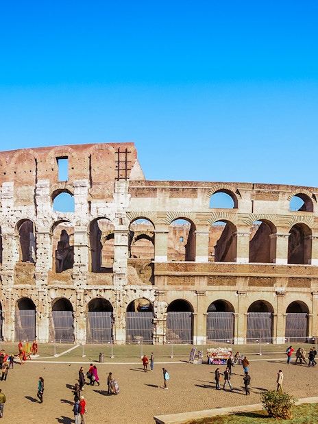 Colosseum in Rome with tourists exploring the exterior on a guided tour.
