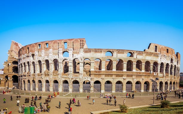 Colosseum in Rome with tourists exploring the exterior on a guided tour.