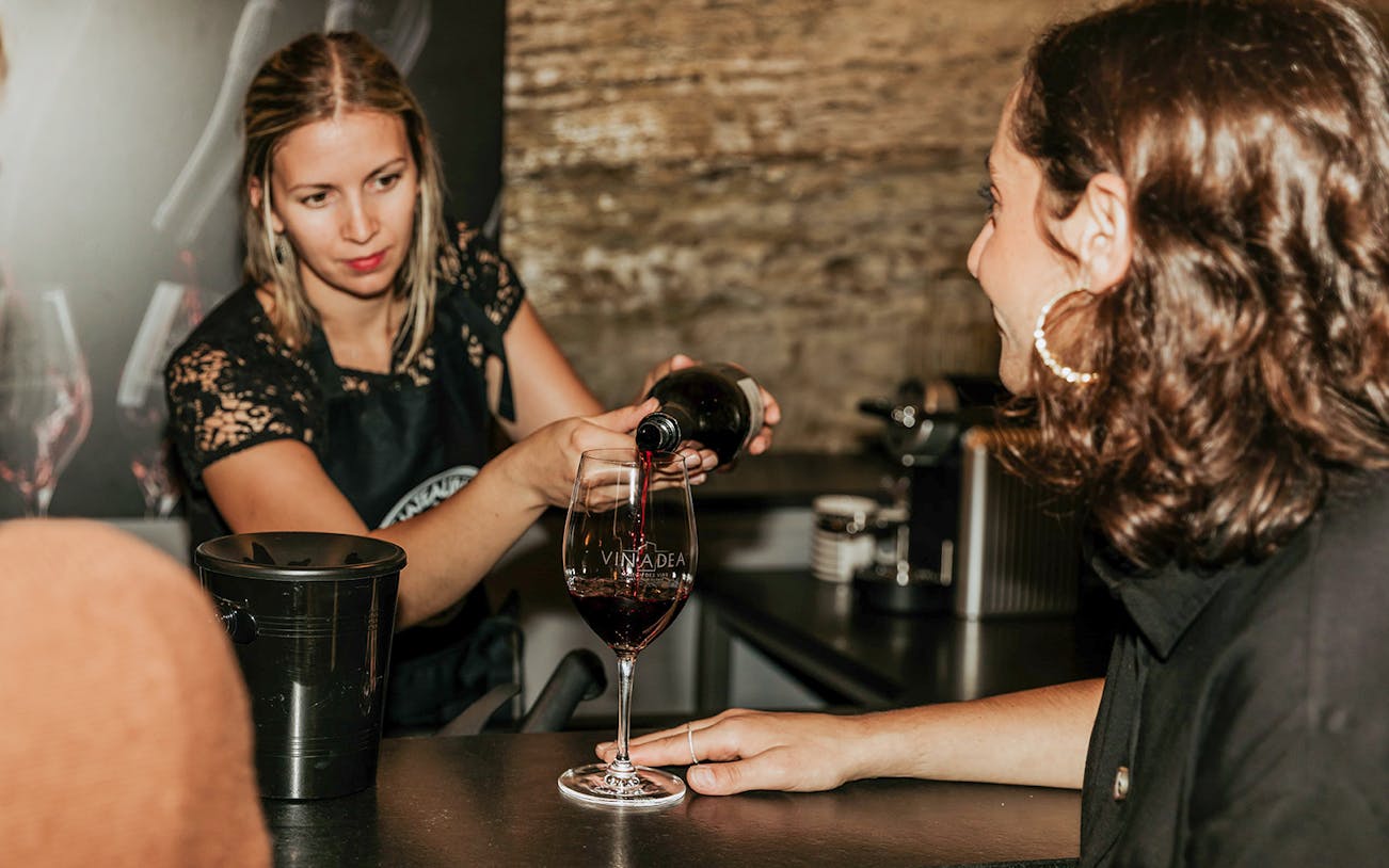 Server pouring red wine during a tasting experience.