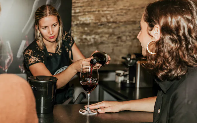 Server pouring red wine during a tasting experience.