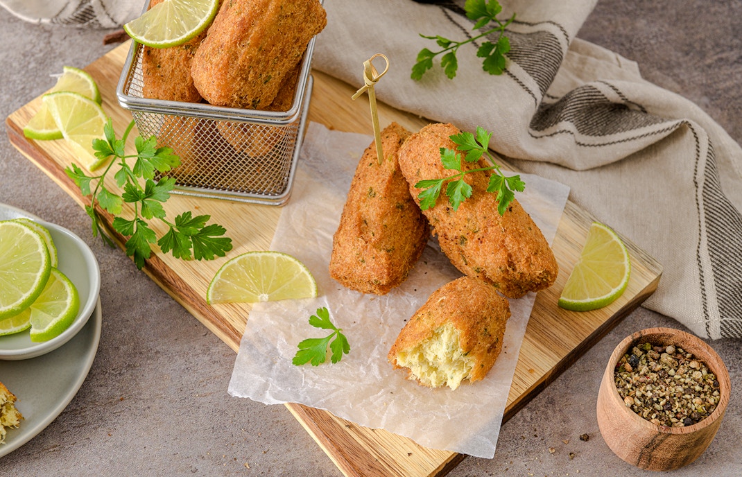 Golden cod cakes with lime slices on a wooden board, Douro Valley.