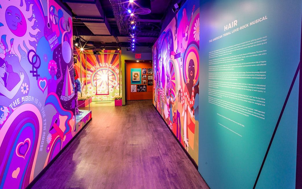 Colorful hallway with vibrant murals and text about the musical "Hair" at The Museum Of Broadway.