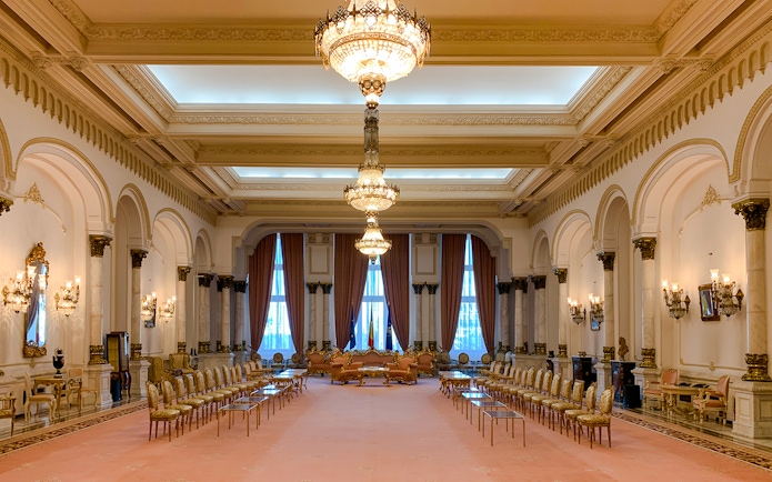 Grand hall with chandeliers and ornate decor inside Palace of Parliament, Bucharest.