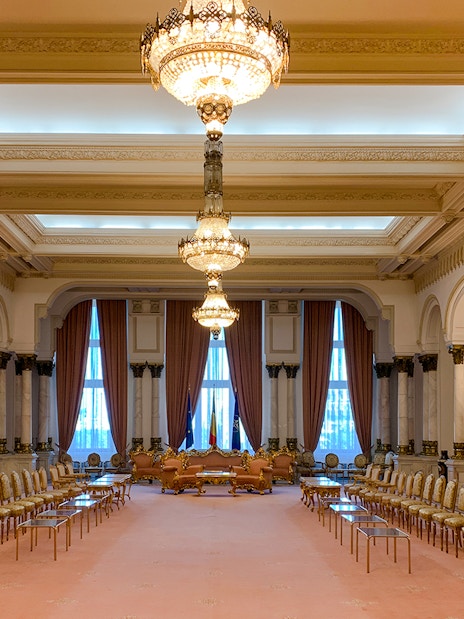 Grand hall with chandeliers and ornate decor inside Palace of Parliament, Bucharest.