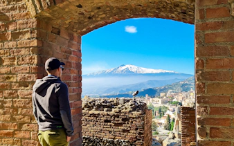 Man viewing Mount Etna from Taormina's ancient theatre.