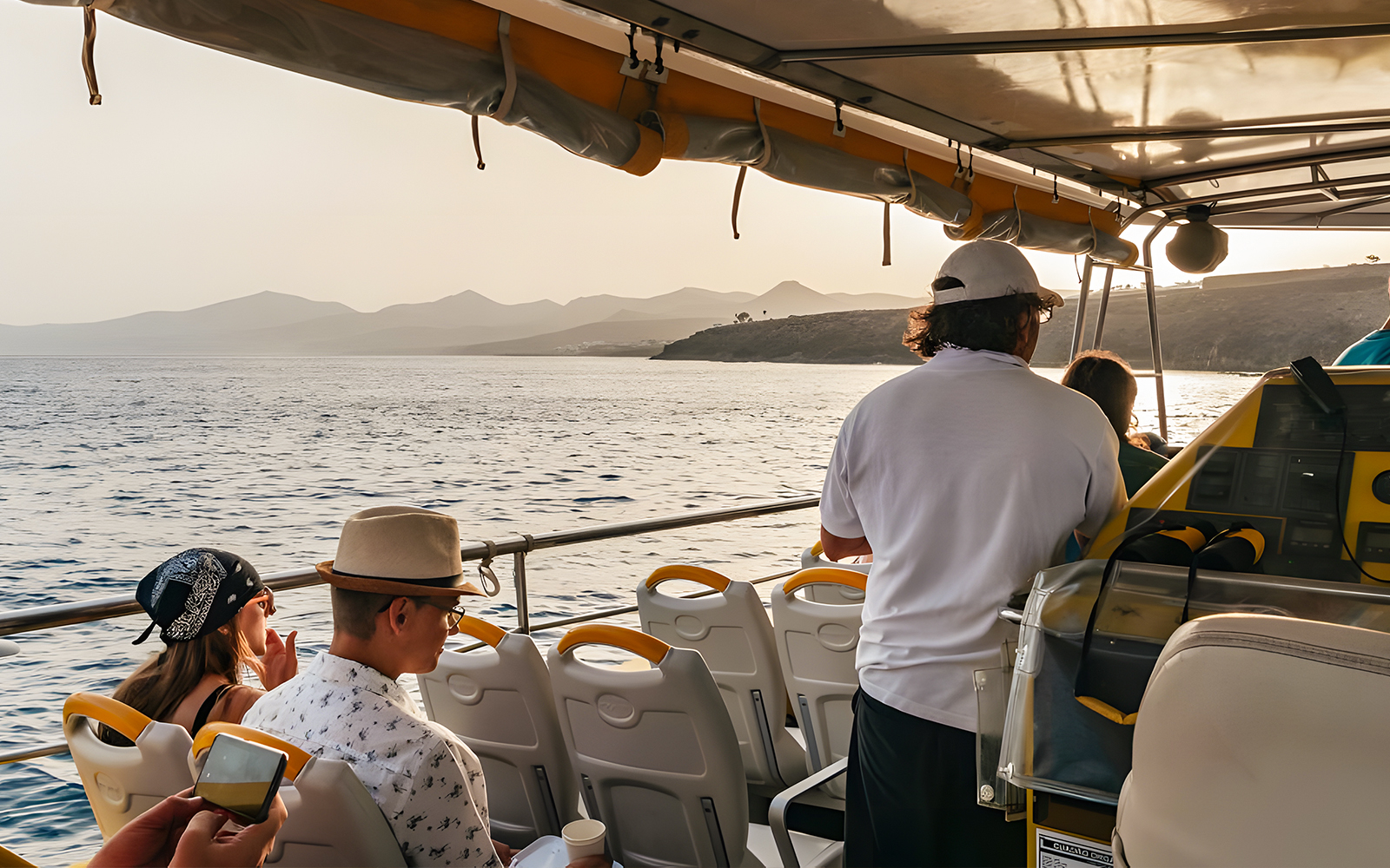 Tourists on a speedboat enjoying a sunset cruise with distant coastal views.