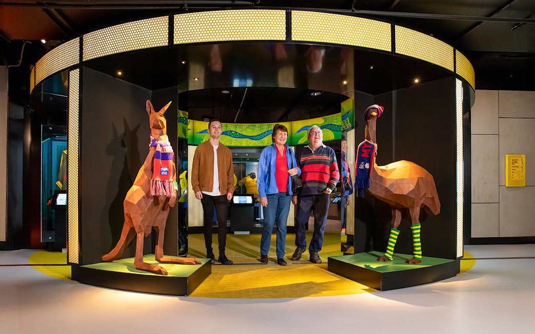 Visitors at Melbourne Cricket Ground tour entrance with kangaroo and emu sculptures.