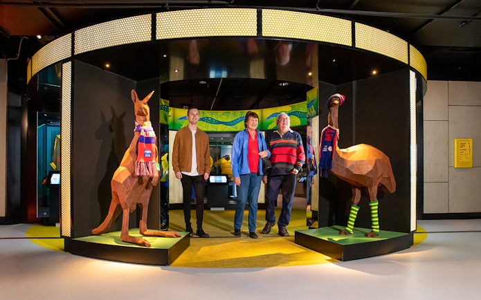 Visitors at Melbourne Cricket Ground tour entrance with kangaroo and emu sculptures.