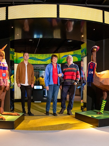 Visitors at Melbourne Cricket Ground tour entrance with kangaroo and emu sculptures.