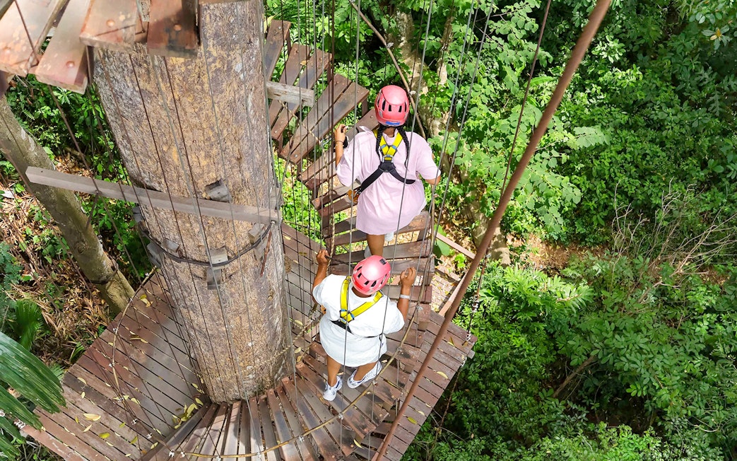 Visitors on a treetop platform at Hanuman World zipline adventure in lush forest.