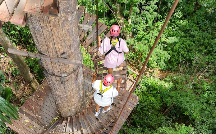 Visitors on a treetop platform at Hanuman World zipline adventure in lush forest.