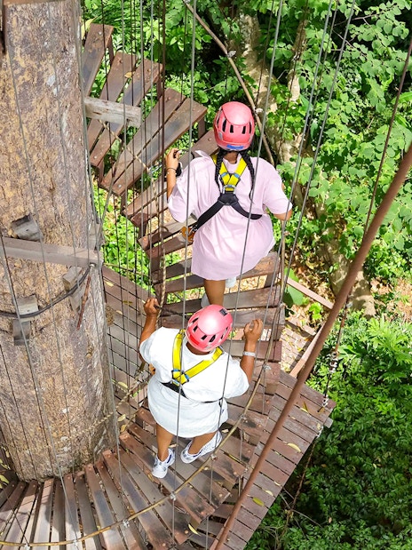 Visitors on a treetop platform at Hanuman World zipline adventure in lush forest.