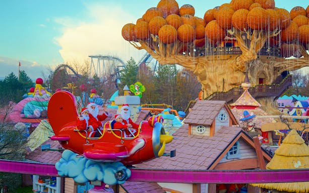 Santa-themed ride at Gardaland Park with whimsical tree and colorful rooftops.