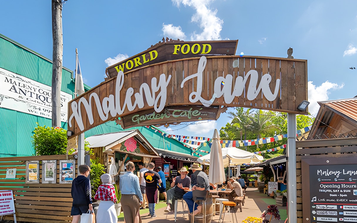 Maleny Lane entrance with visitors at Eumundi Markets, featuring cafes and shops.
