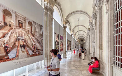 Tourists viewing art in the Royal Palace of Madrid corridor.