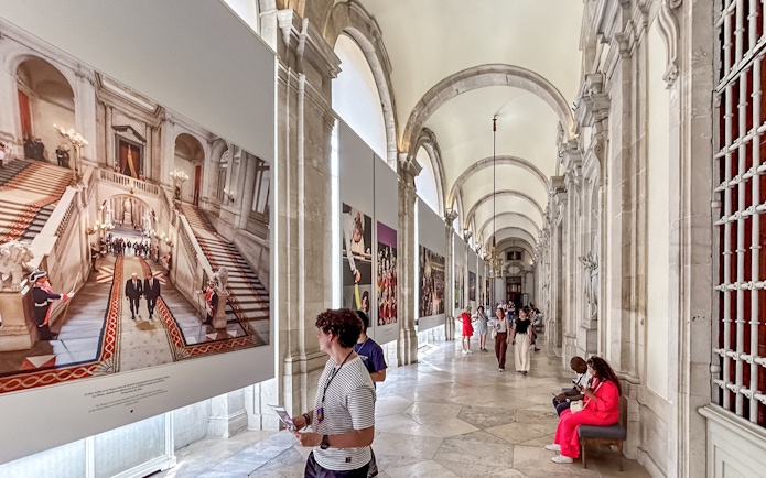 Tourists viewing art in the Royal Palace of Madrid corridor.