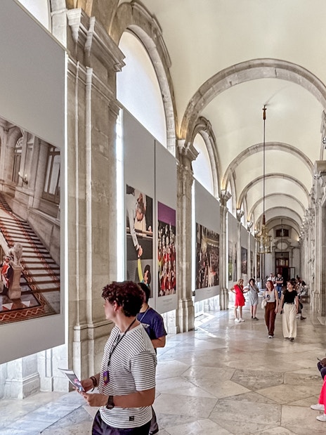 Tourists viewing art in the Royal Palace of Madrid corridor.