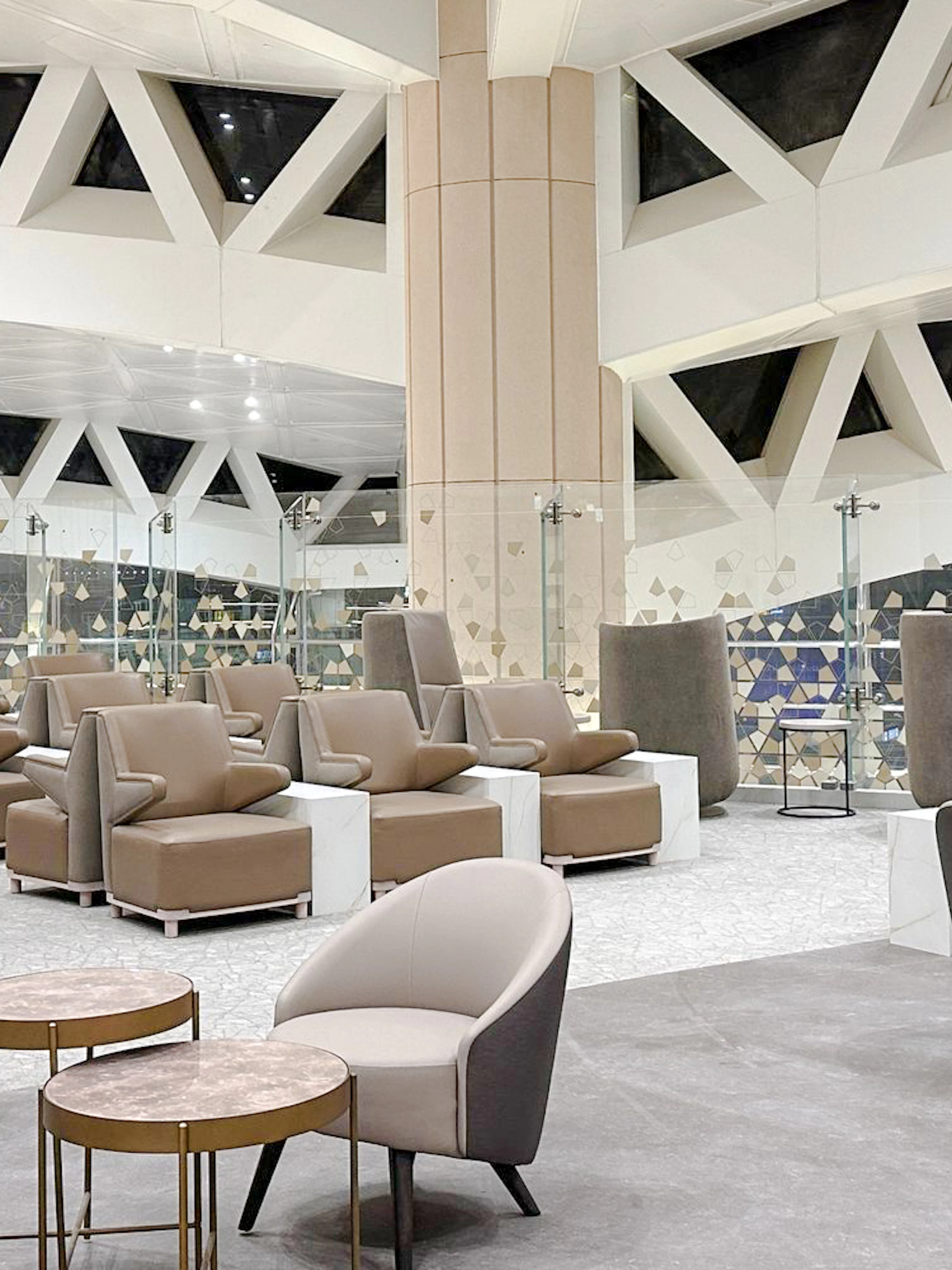 Sitting area with modern chairs and tables at Plaza Premium Lounge, Riyadh airport.