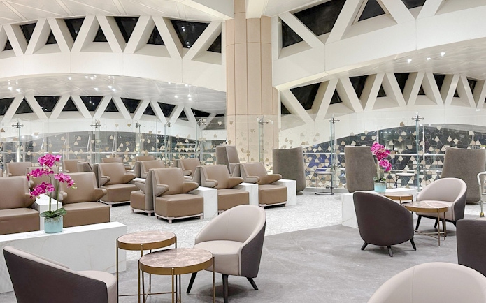 Sitting area with modern chairs and tables at Plaza Premium Lounge, Riyadh airport.