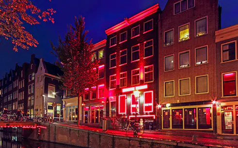 Amsterdam Red Light District buildings illuminated at night along a canal.