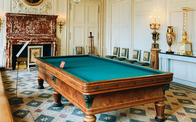 Billiard room with ornate fireplace and decor at the Palace of Versailles.
