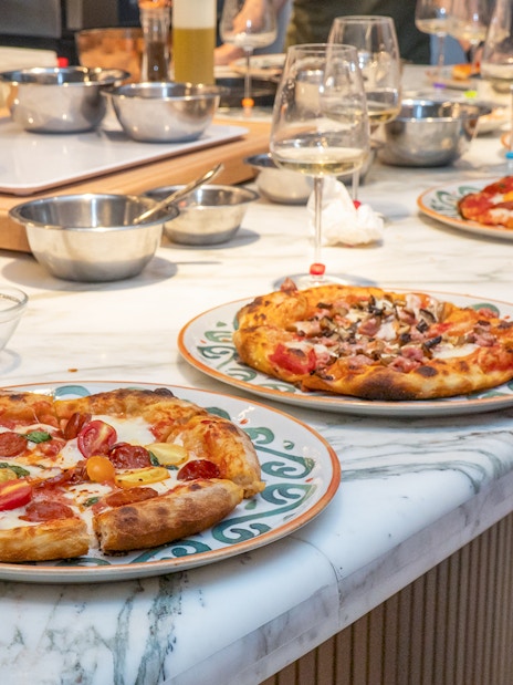 Freshly made pizzas on a marble table at a pizza making class in Rome.