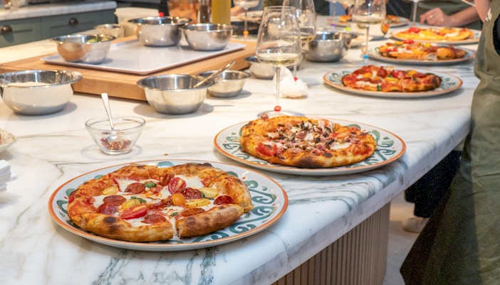 Freshly baked pizza on a wooden table during a pizza-making class in Rome.