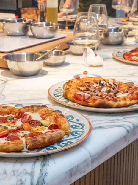 Freshly made pizzas on a marble table at a pizza making class in Rome.
