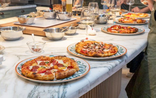 Freshly made pizzas on a marble table at a pizza making class in Rome.